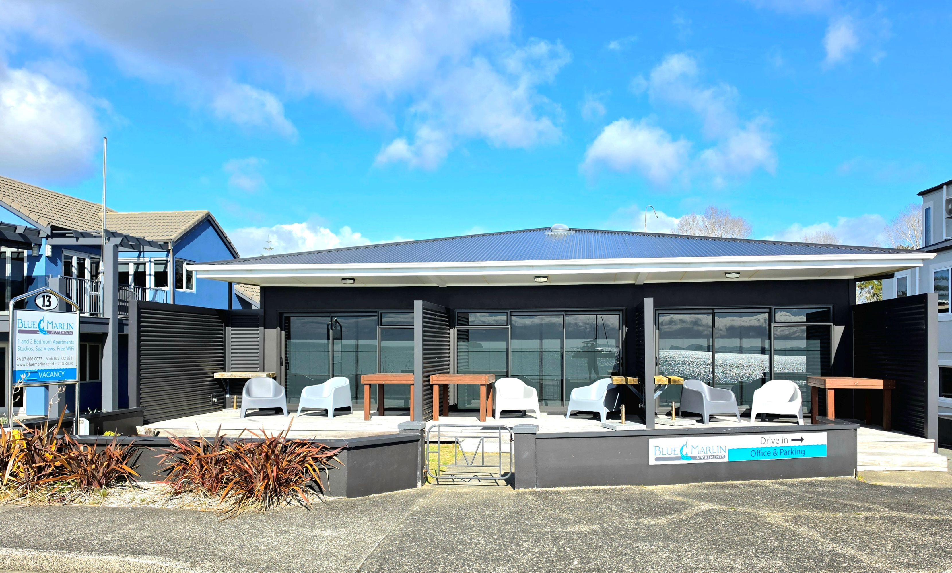 A modern building with a covered outdoor seating area and a sign indicating office and parking.