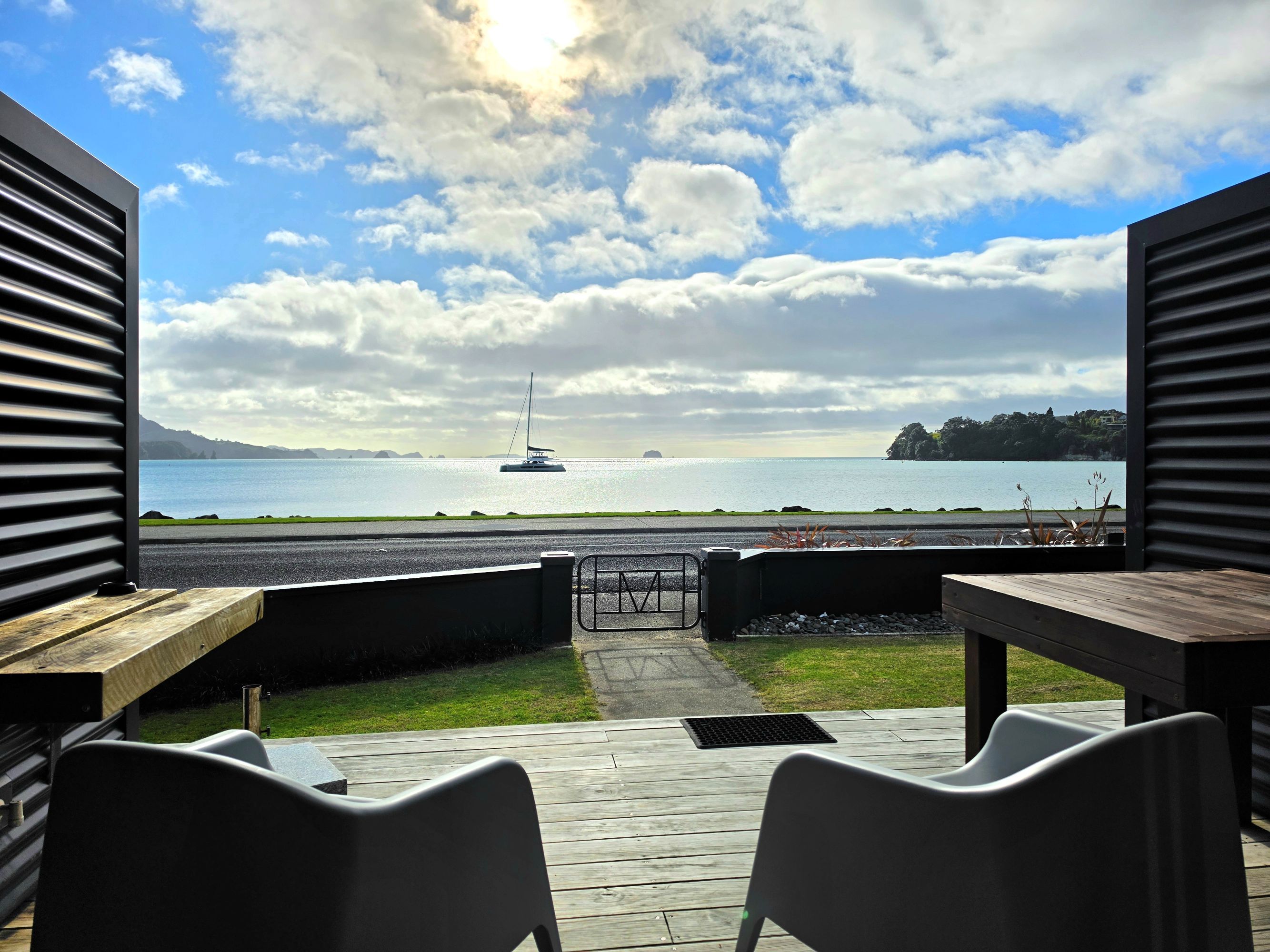 Eine Terrasse im Freien mit Blick auf einen See und ein Segelboot.