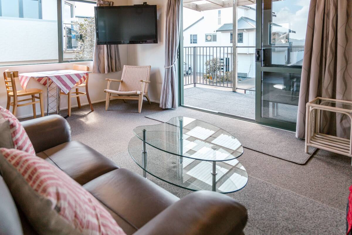 A living room with a glass coffee table, a sofa, and a dining table with chairs.