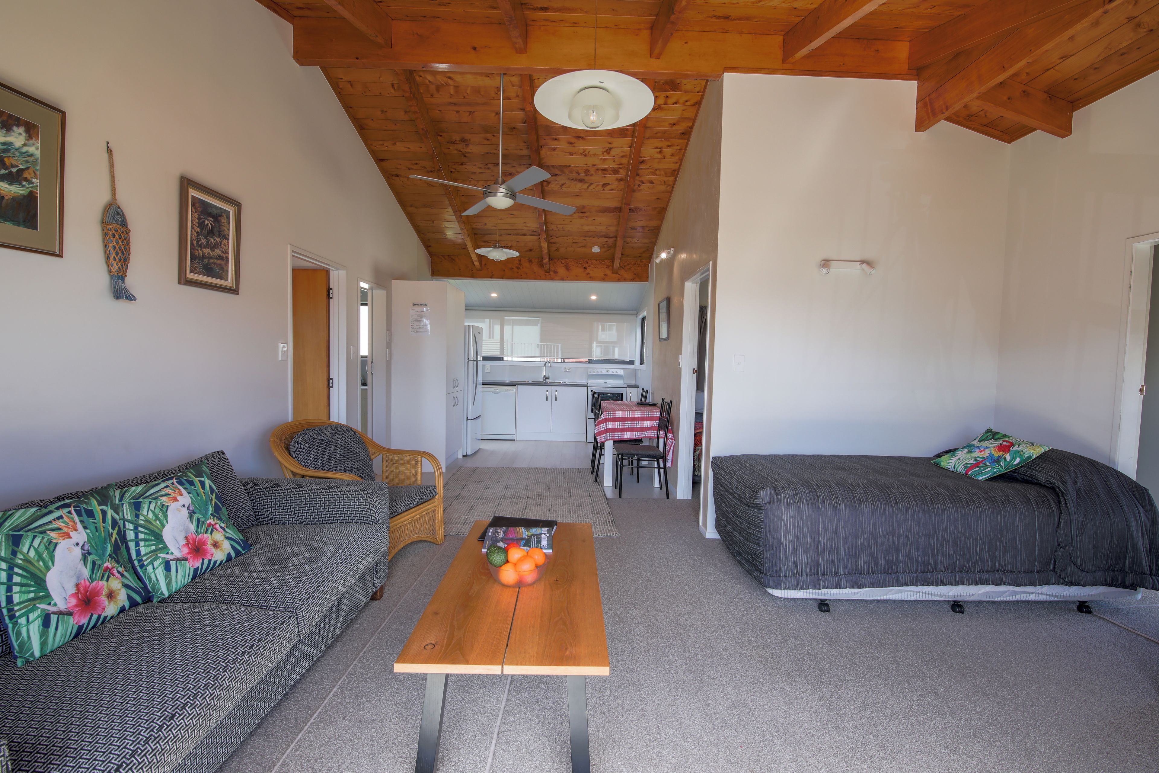 A compact living space with a sofa, a bed, a dining table, and a kitchen area.