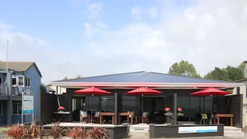 Relax in the covered outdoor seating area with tables and chairs, surrounded by a beautifully landscaped garden.