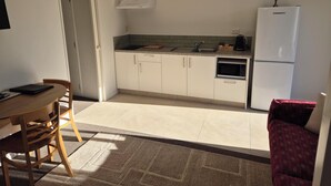 Een compacte keuken met een magnetron, fornuis en koelkast.