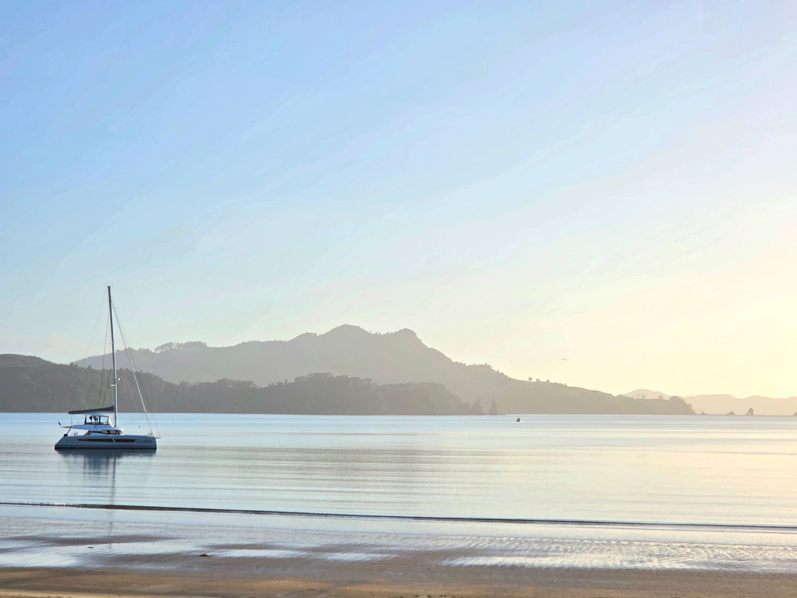 A calm body of water with a sailboat anchored near the shore.