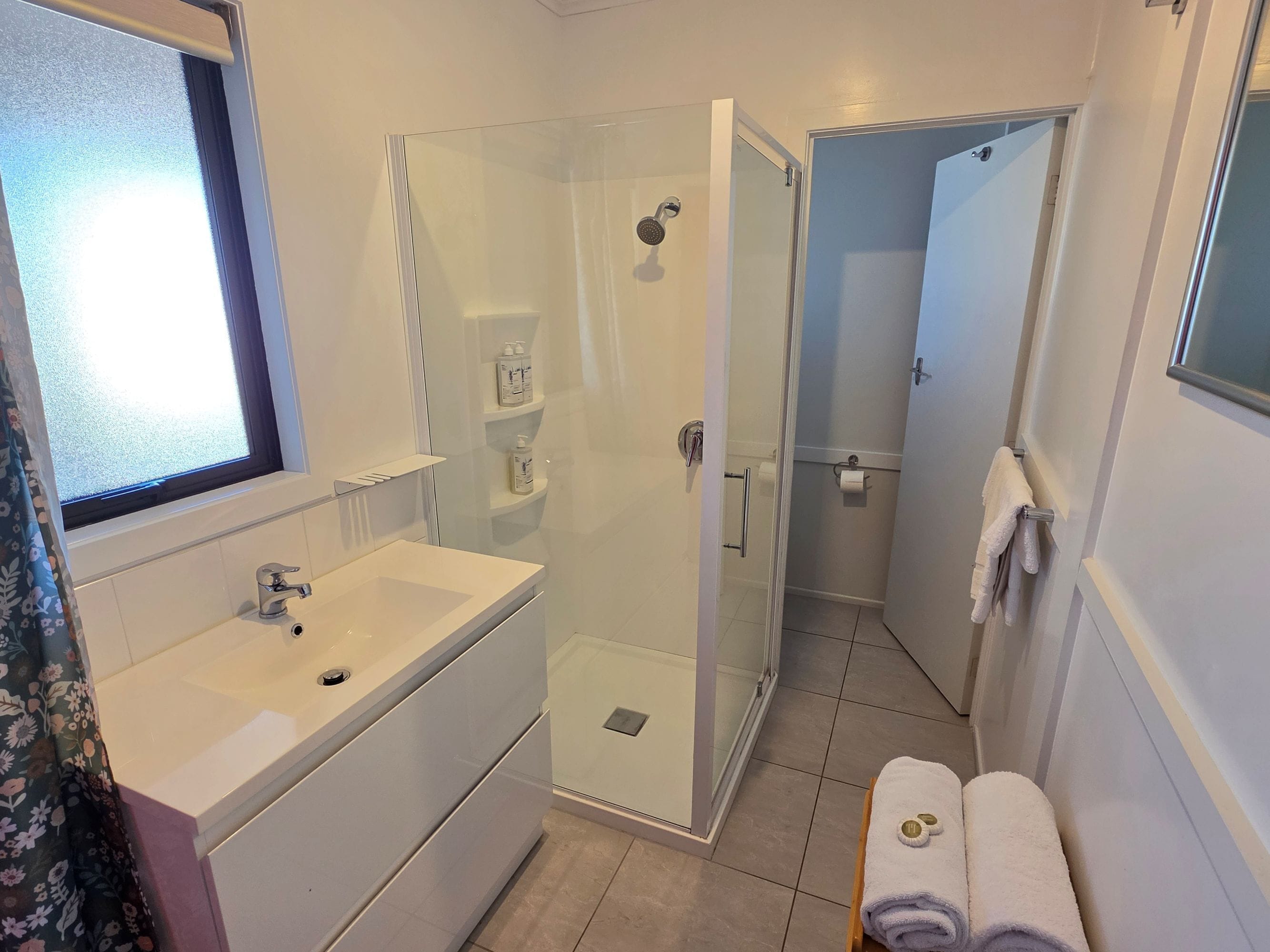 Une salle de bain moderne avec une douche à parois de verre, un lavabo avec un miroir et un porte-serviettes.