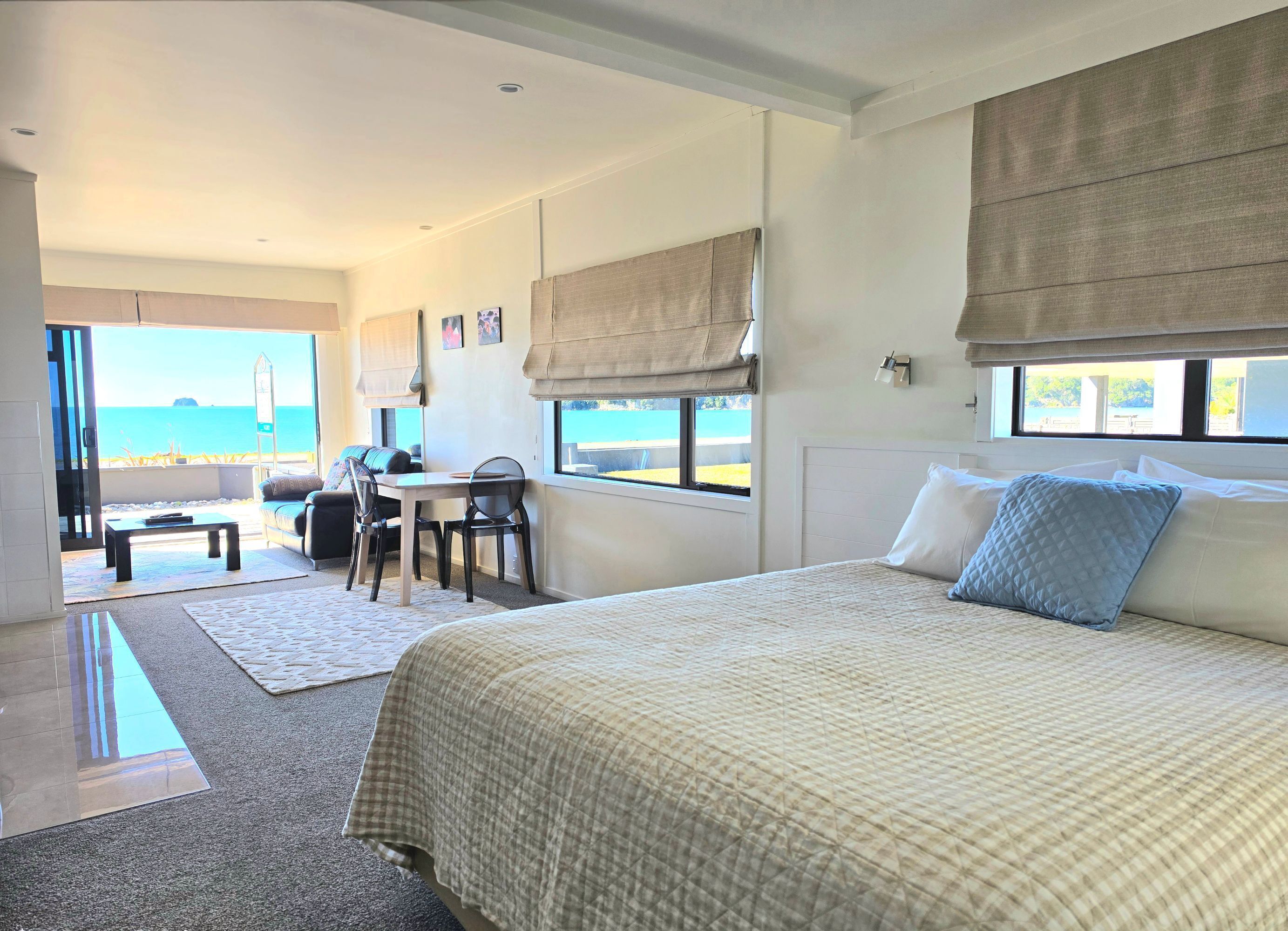 A hotel room with a bed, a desk, and a view of the sea.
