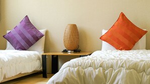 A hotel room with two beds, each with a white duvet, a small wooden table with a woven lamp, and two pillows, one purple and one orange. - BONFIRE HOSTEL Osaka (Osaka)