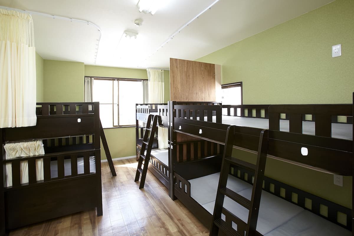 Ein Zimmer mit Etagenbetten, einer Leiter und einem Fenster mit Vorhängen.