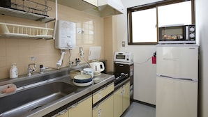 A compact kitchen with a sink, stove, microwave, and refrigerator. - BONFIRE HOSTEL Osaka (Osaka)