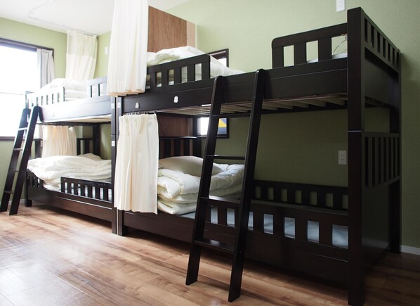 Habitación con literas, una escalera, cortinas en la ventana y piso de madera.