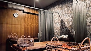 A room with a stone wall, wooden paneling, a clock, and wicker baskets on a bench. - The Loft Room Nimman (Chiang Mai)