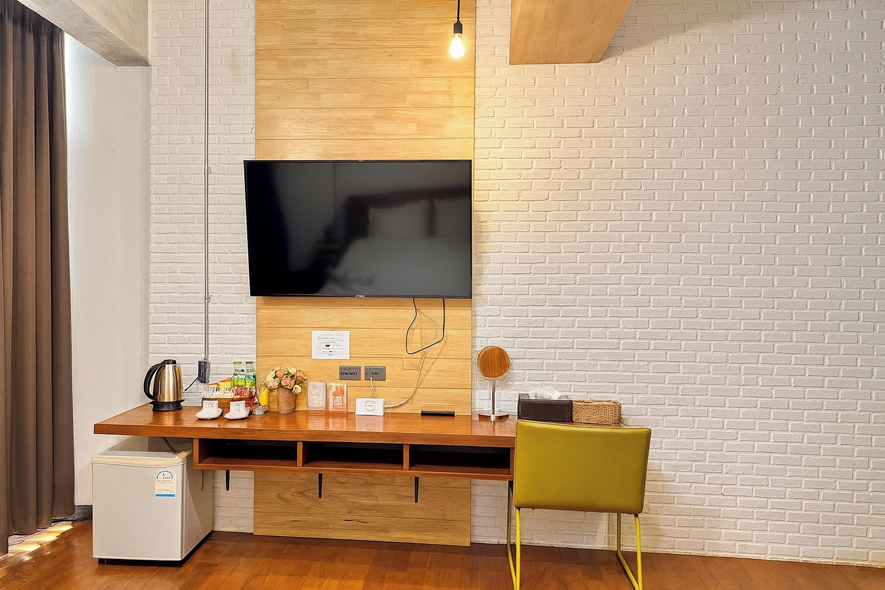 A modern kitchen with a built-in TV, wooden countertop, and a compact fridge.
