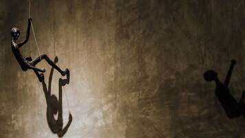 A person hanging from a rope against a textured wall.