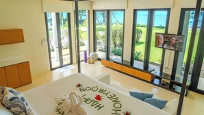 A hotel room with a large bed, a view of the sea, and a TV on the wall. - The Anda Mani Khaolak Beachfront Villas (Thai Mueang)