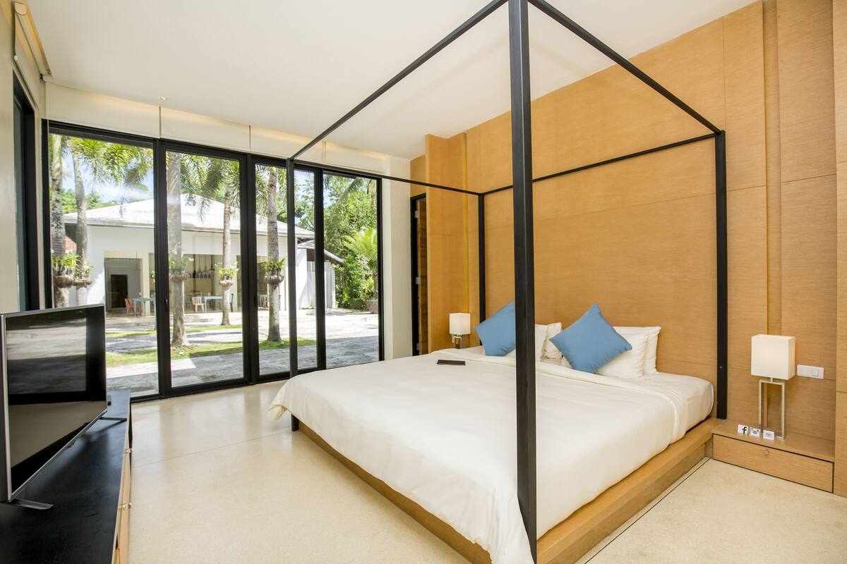 Un dormitorio moderno con una cama con dosel, un televisor de pantalla plana y vistas al exterior.