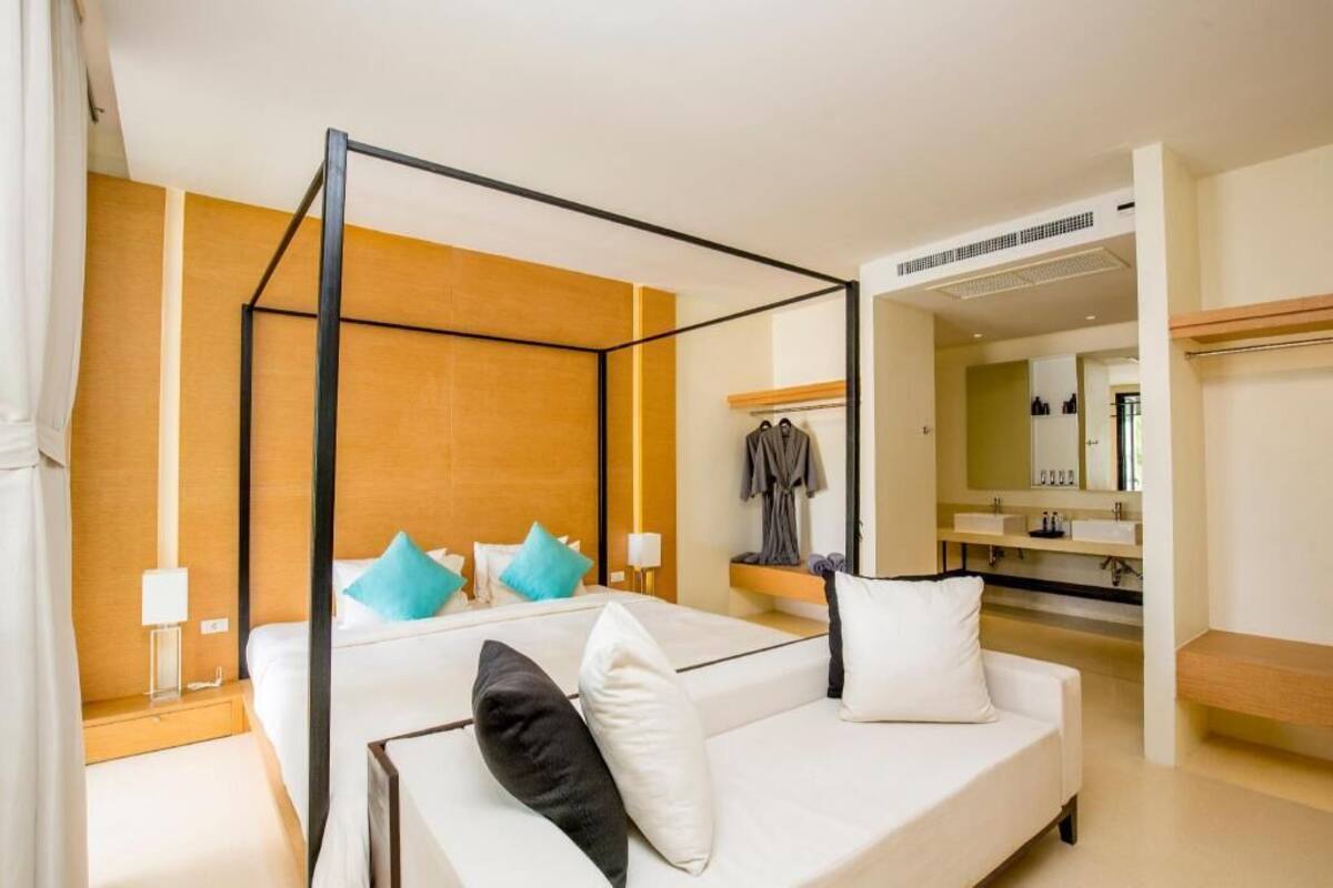 Una habitación de hotel moderna con una cama con dosel, una tocador con espejo y un vestidor.