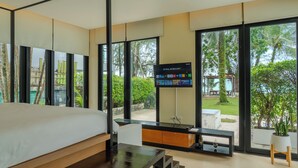 A modern bedroom with a large bed, a TV mounted on the wall, and a view of the outdoors. - The Anda Mani Khaolak Beachfront Villas (Thai Mueang)