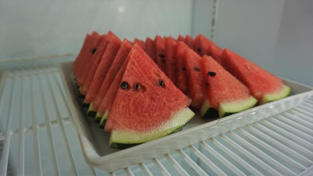 En kølet display med vandmelon skåret i skiver, arrangeret i række.