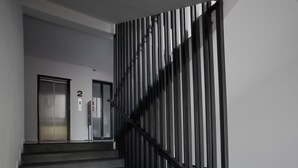 A modern staircase with a black railing and a number '2' sign on the wall. - iWualai Hotel (Chiang Mai)