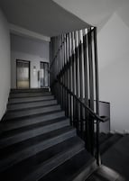 A modern staircase with a black railing and a number '2' sign on the wall.