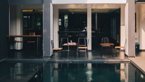A modern building with a swimming pool, outdoor seating, and a person on a balcony. - iWualai Hotel (Chiang Mai)