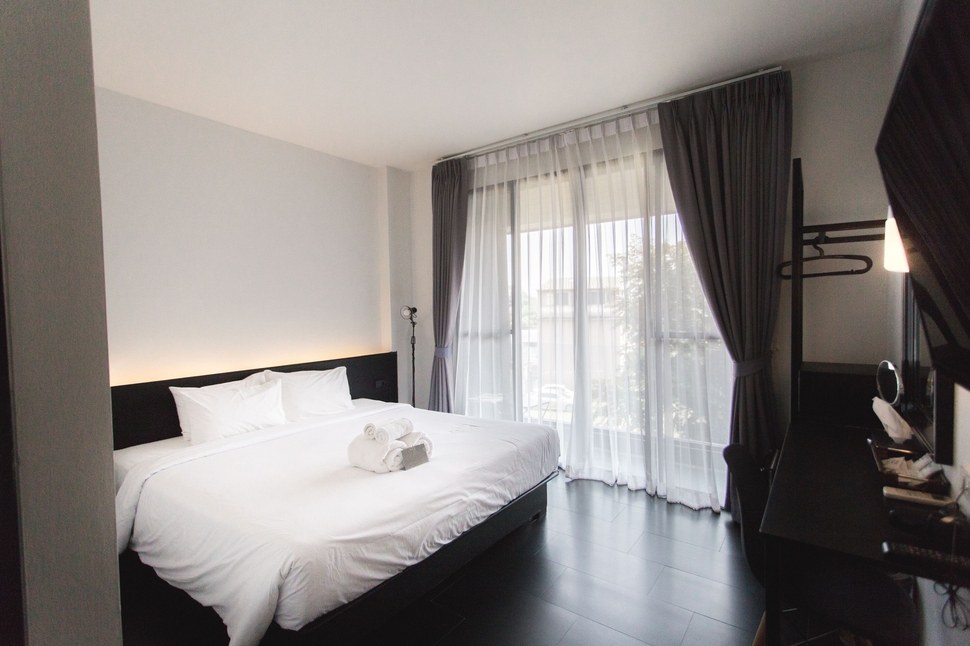 Une chambre d’hôtel avec un grand lit, un bureau avec une chaise et une fenêtre avec des rideaux.