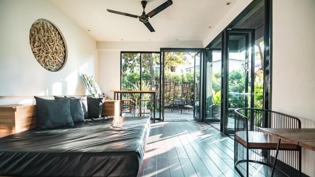 A modern bedroom with a bed, a ceiling fan, and a view of the outdoors through large sliding doors. - iWualai Hotel (Chiang Mai)