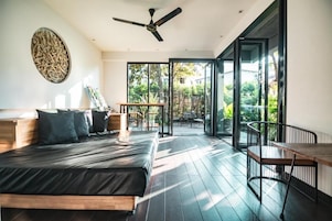A modern bedroom with a bed, a ceiling fan, and a view of the outdoors through large sliding doors.