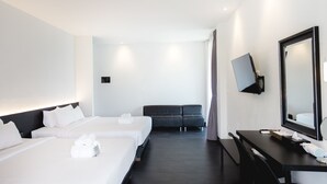 A hotel room with three beds, a desk, a chair, a TV, and a large mirror. - iWualai Hotel (Chiang Mai)