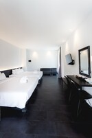 A hotel room with three beds, a desk, a chair, a TV, and a large mirror.