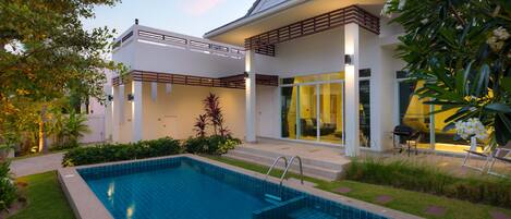 A modern house with a swimming pool, a covered patio, and a well-maintained garden.