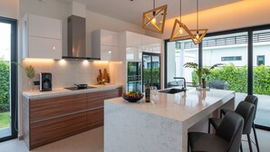 Una cocina moderna con una isla central, armarios de madera e iluminación colgante.