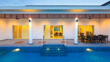 A modern hotel with a swimming pool, large sliding glass doors, and a patio area with outdoor seating.
