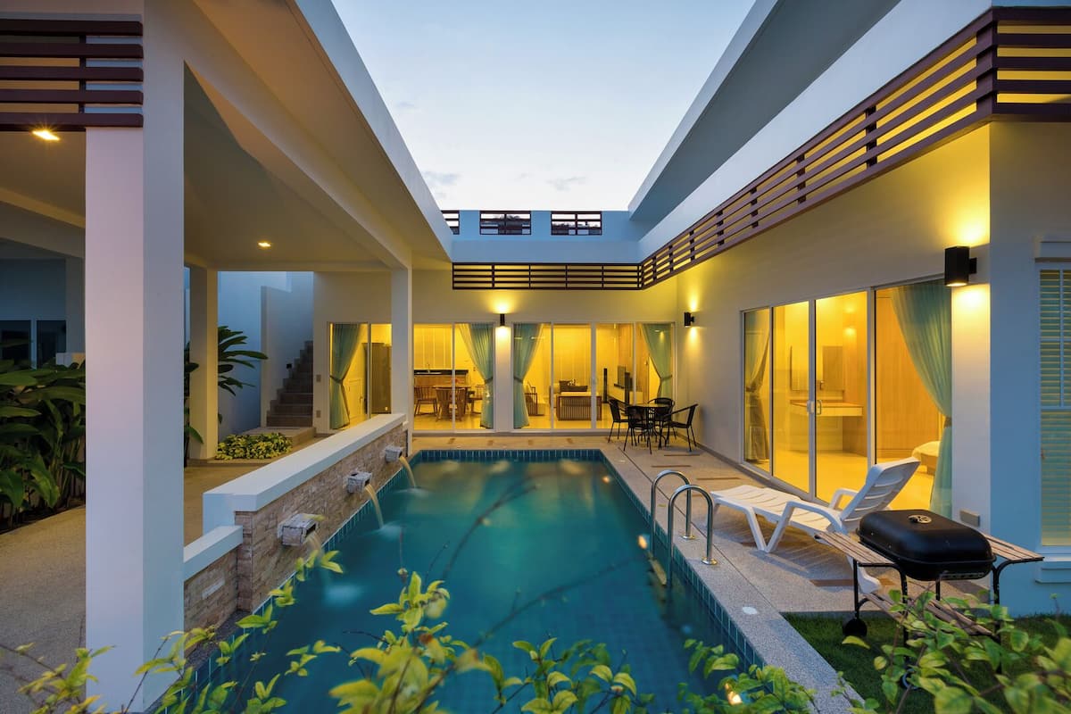 Un área de piscina moderna con vista despejada, sillas de descanso y una zona de comedor.