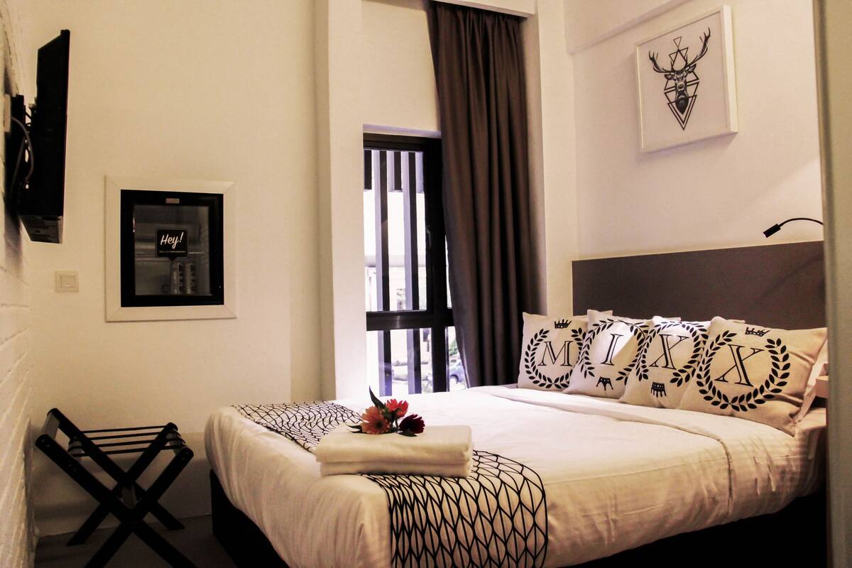A neatly made bed with patterned pillows, a framed picture on the wall, and a towel on the side.