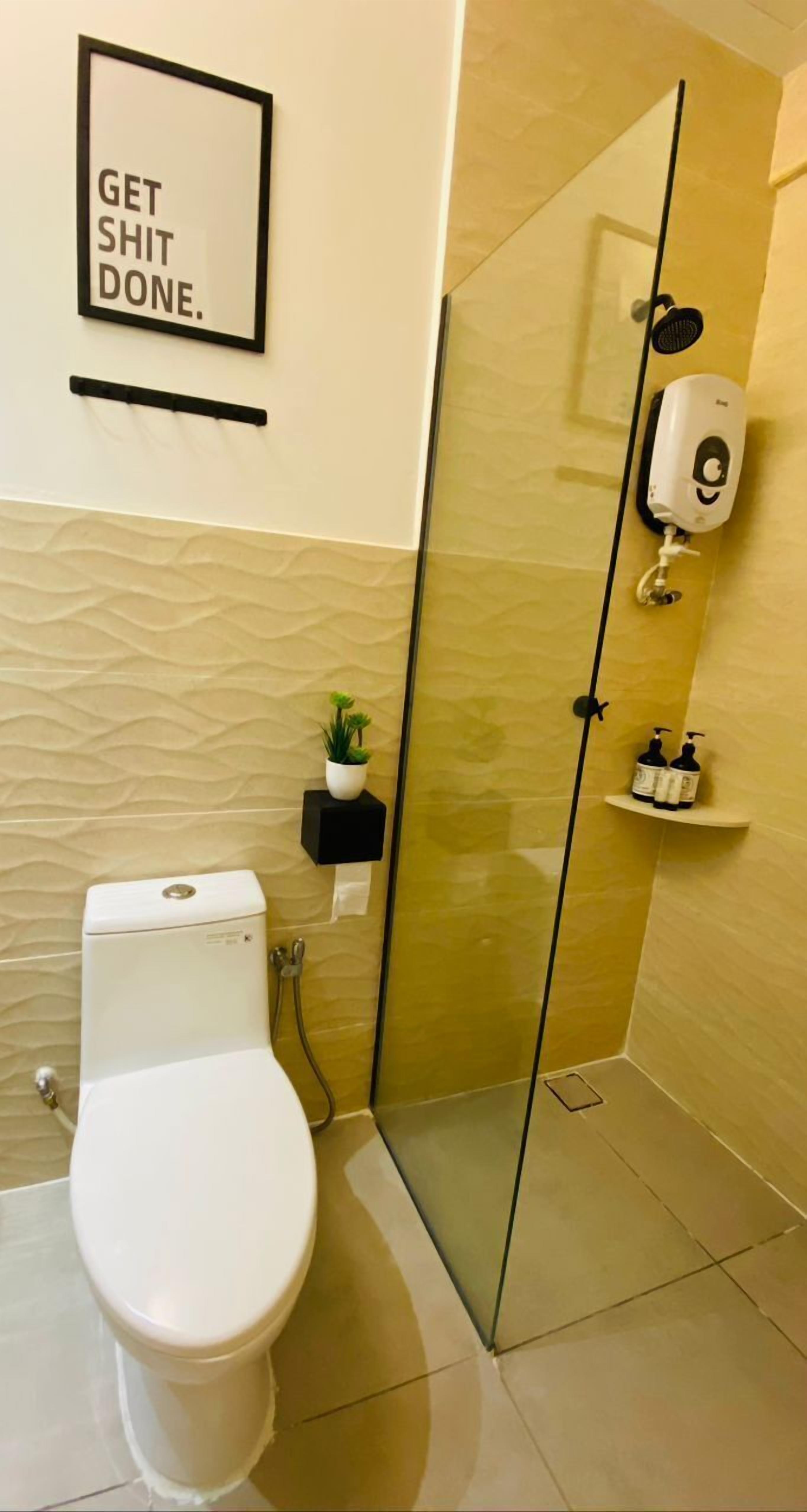 Une salle de bain moderne équipée de toilettes, d’une douche à parois de verre, d’un distributeur de savon liquide et d’une petite plante en pot.