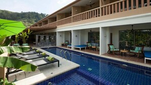 Un espace piscine avec des chaises longues et un coin salon abrité.