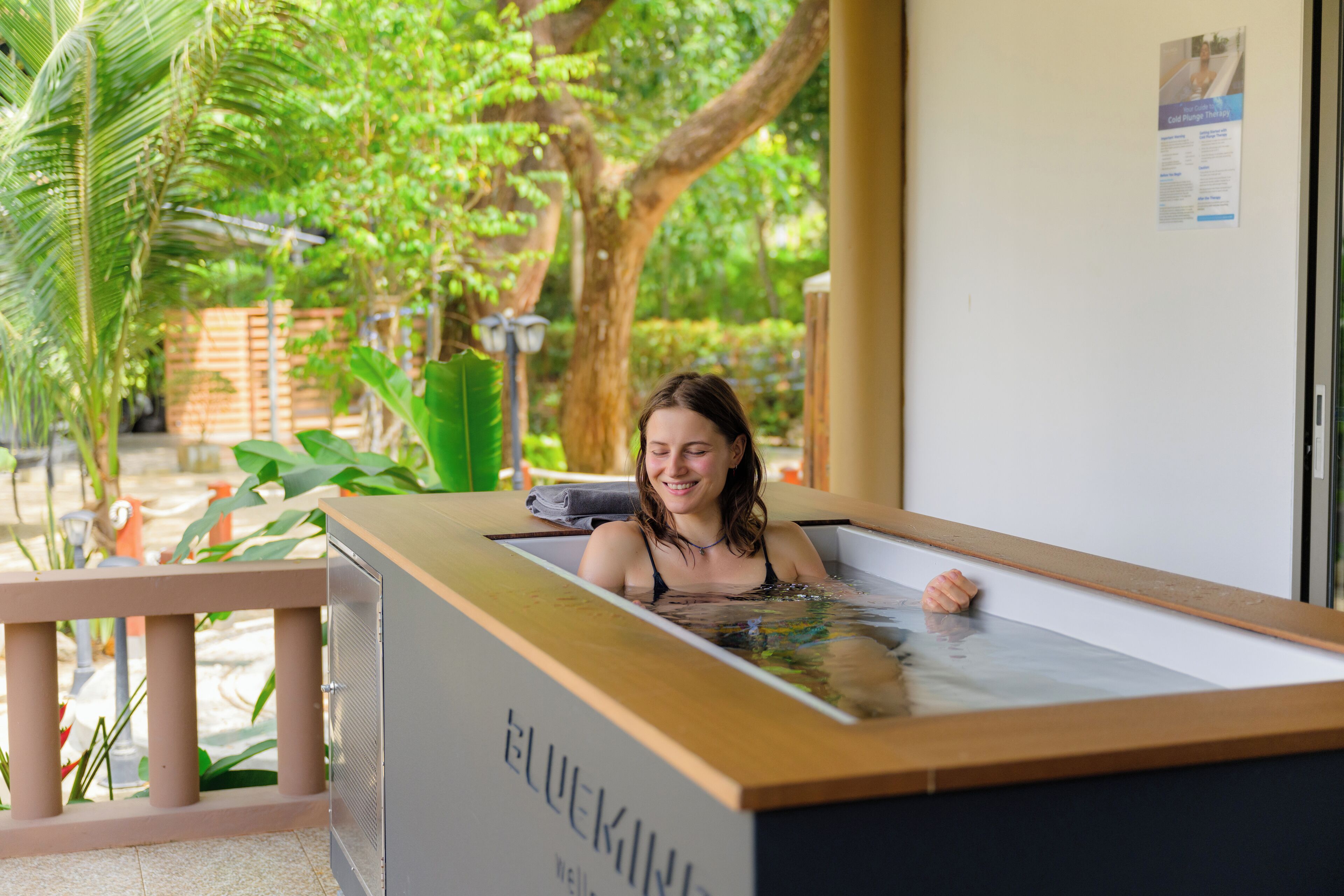 Una persona en un jacuzzi con estructura de madera y la palabra "BLUEKIN" escrita en él.