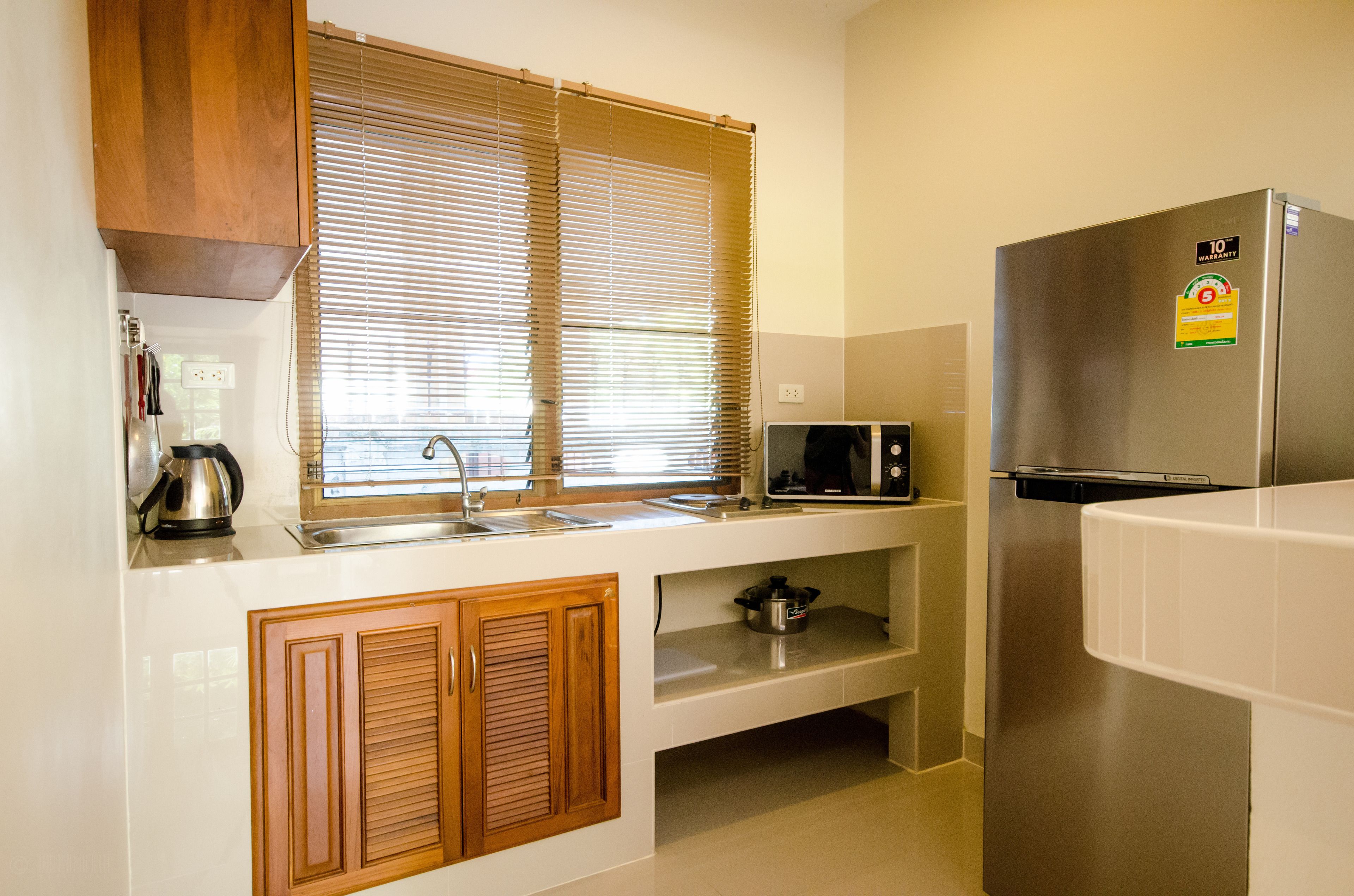 Una cocina moderna con armarios de madera, un refrigerador de acero inoxidable, un microondas y una tetera.