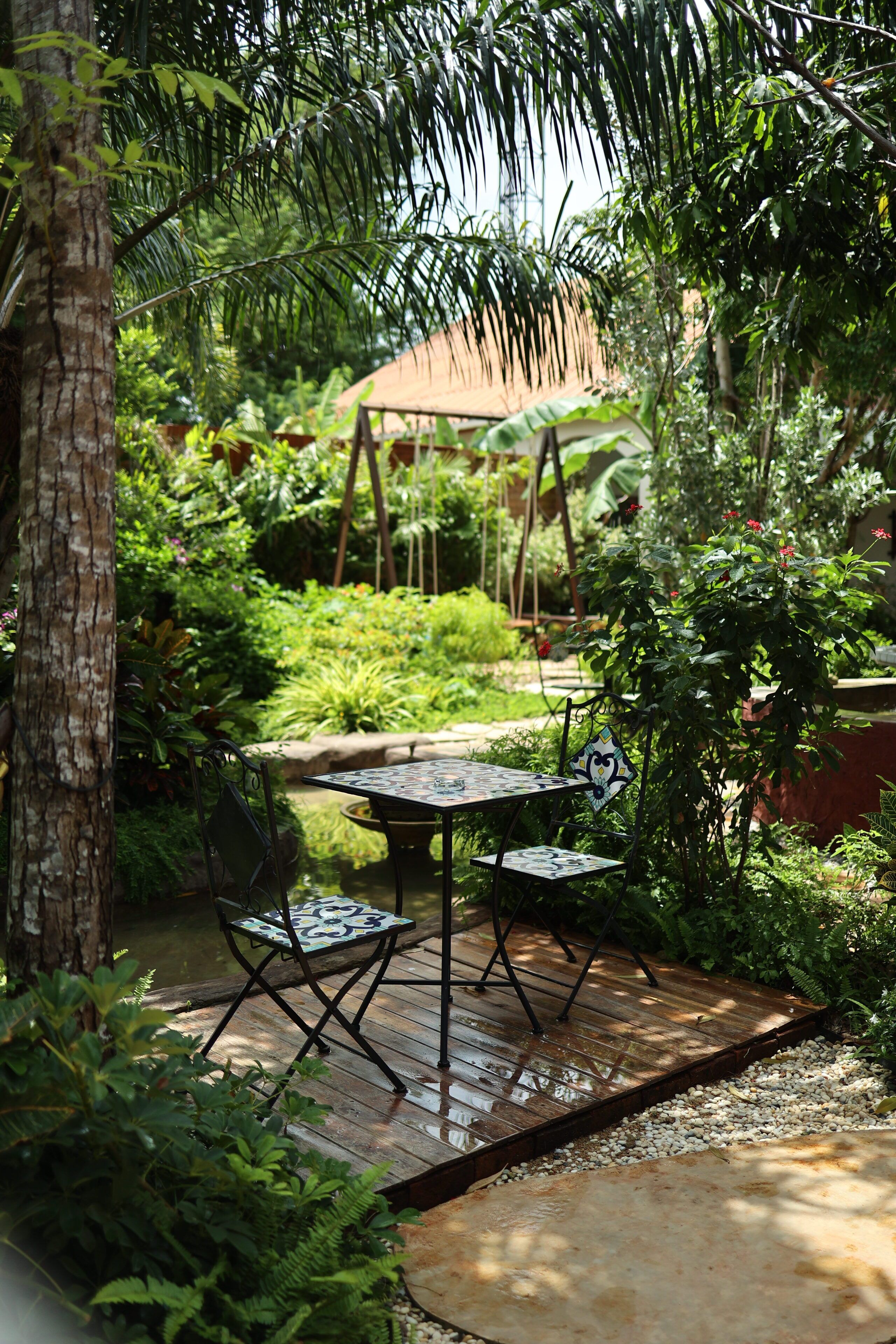 An outdoor patio area with a wooden deck, metal chairs, and a table.