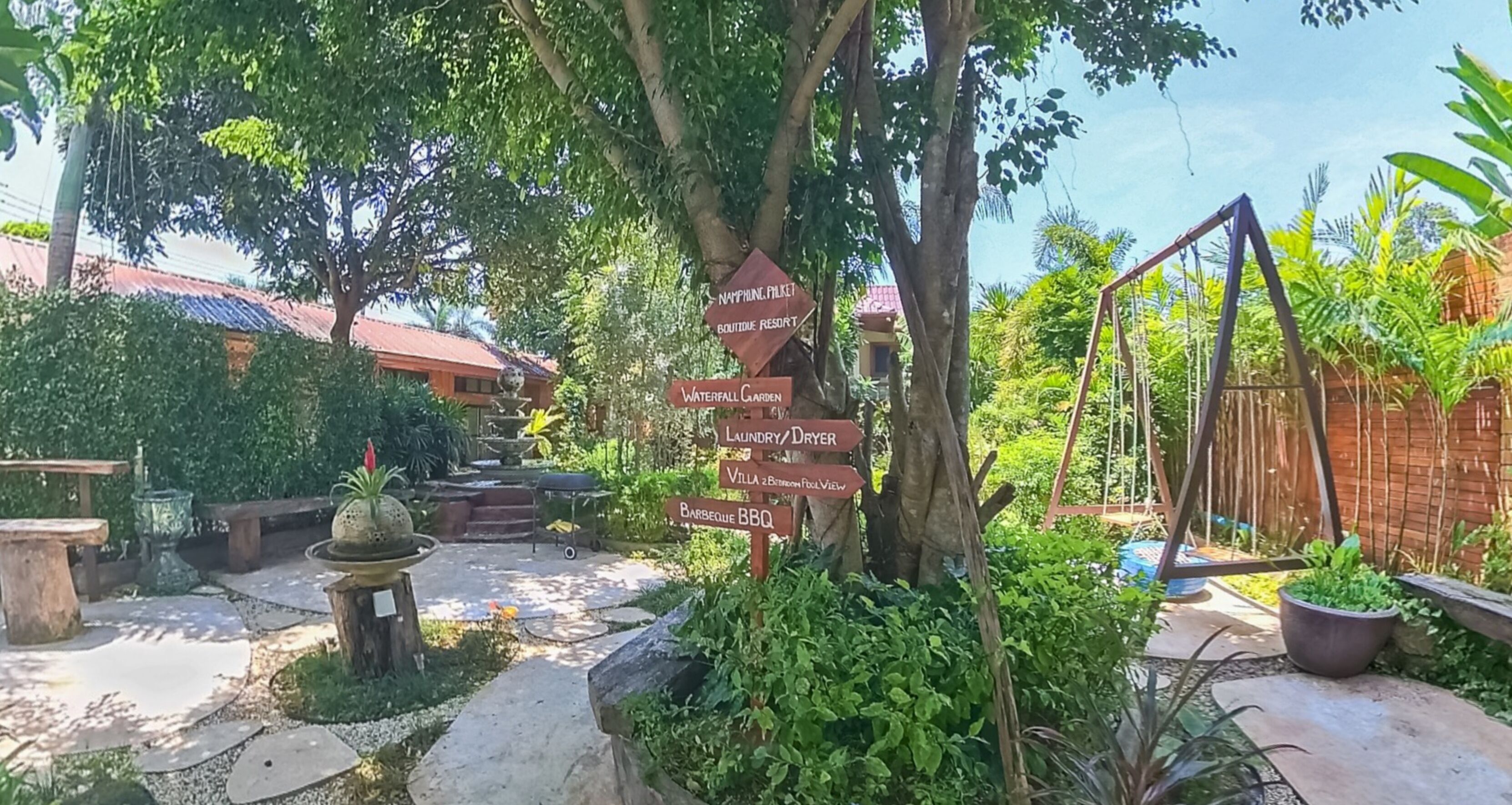 Ein Wegweiser mit Angaben zu verschiedenen Annehmlichkeiten, darunter ein exklusives Resort, ein Wasserfallgarten, eine Wasch-/Trockenmöglichkeit, eine Villa und ein Grillplatz.