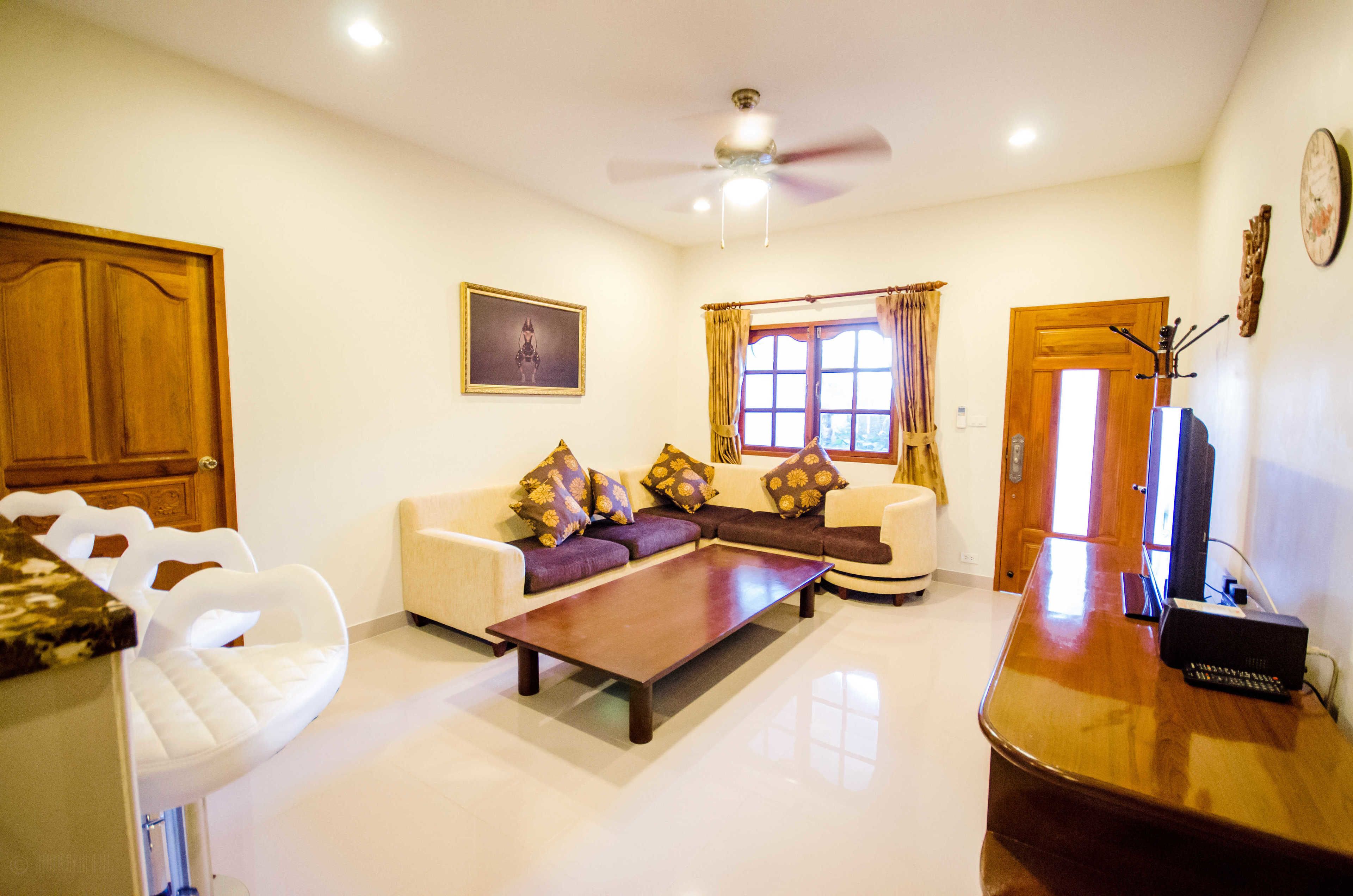 A living room with a sofa, a coffee table, a television, and a ceiling fan.
