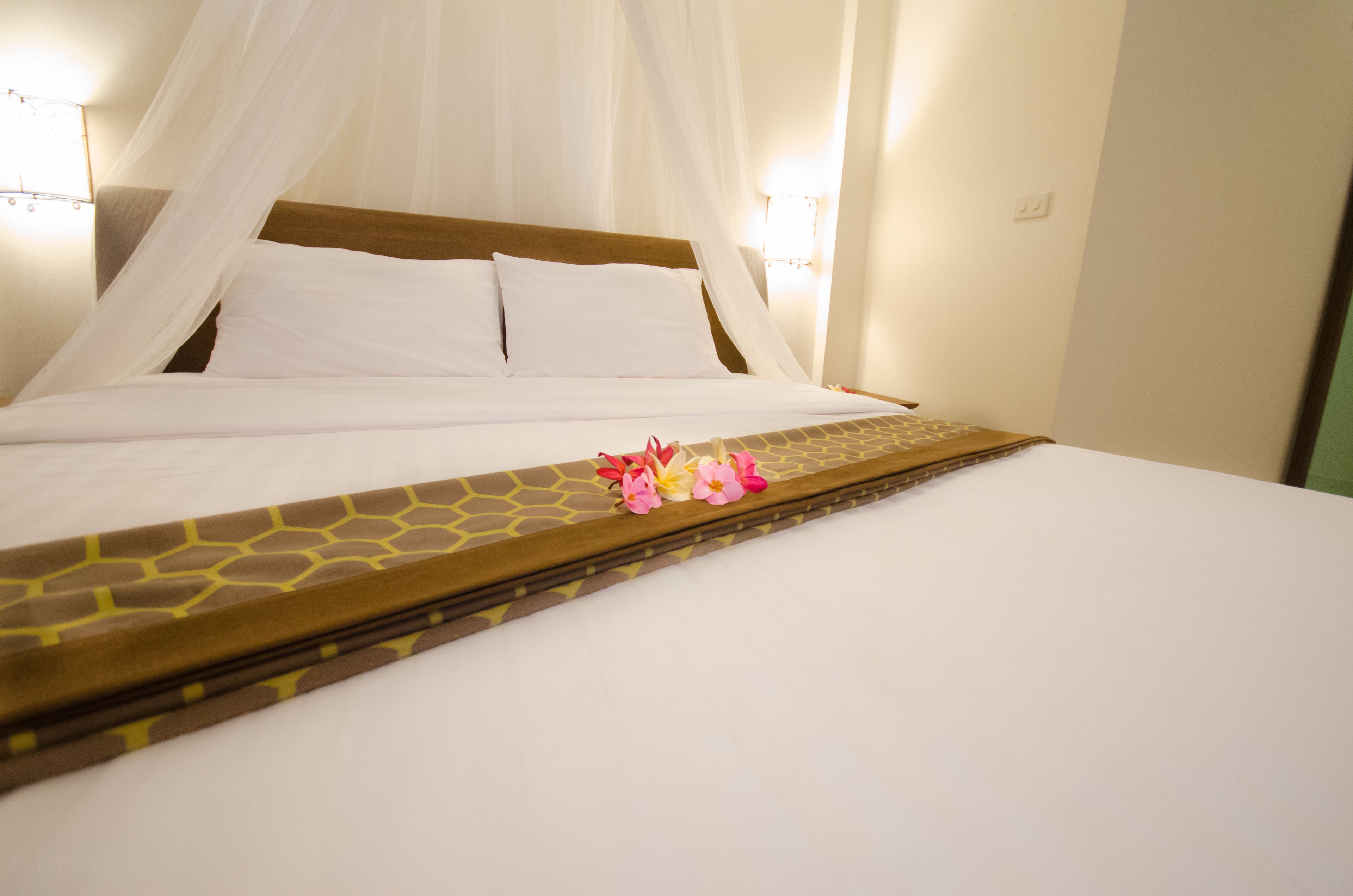 A bed with white linens, a wooden headboard, and a canopy.