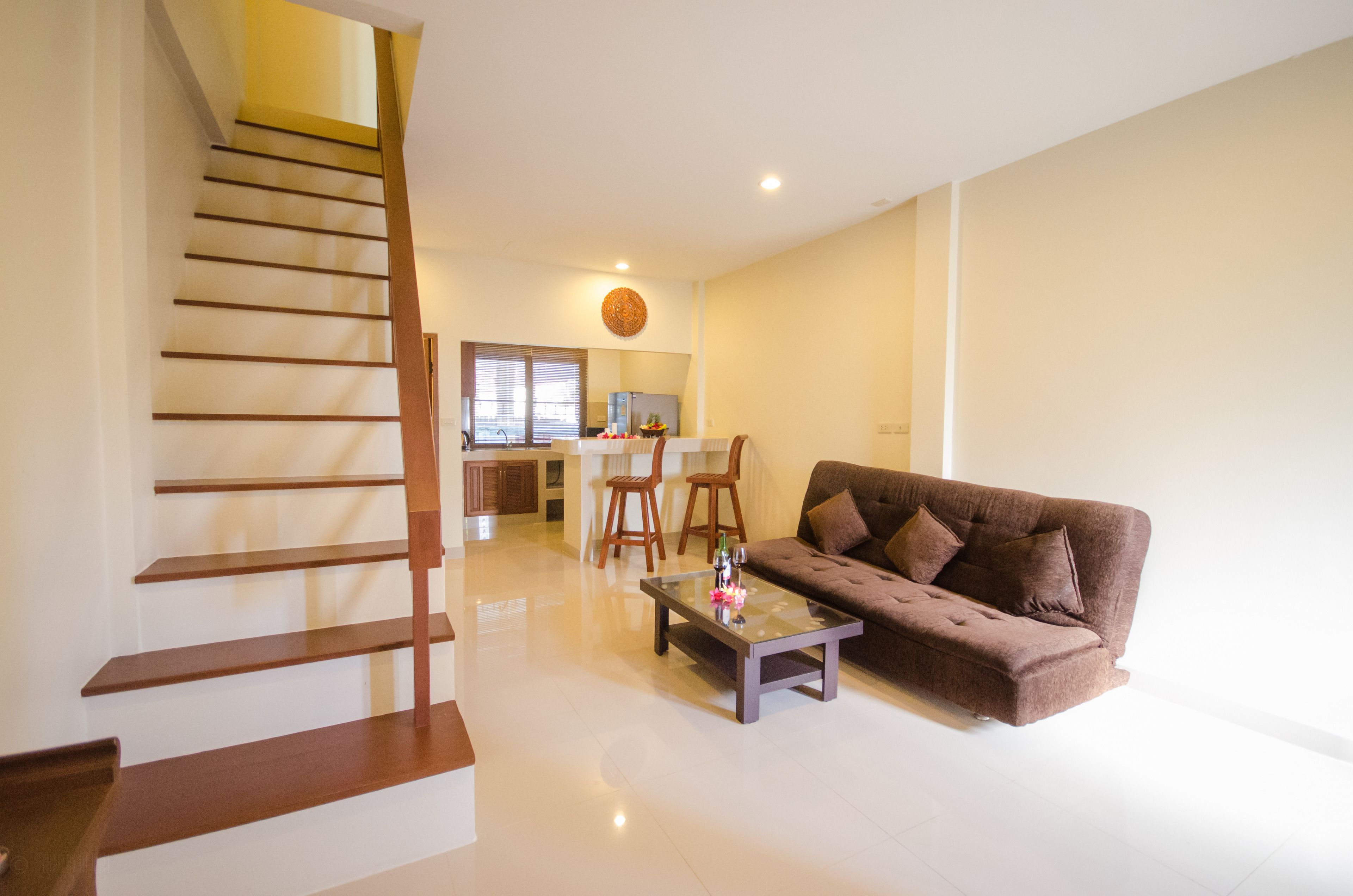 A modern living room with a staircase, a brown sofa, and a glass coffee table.