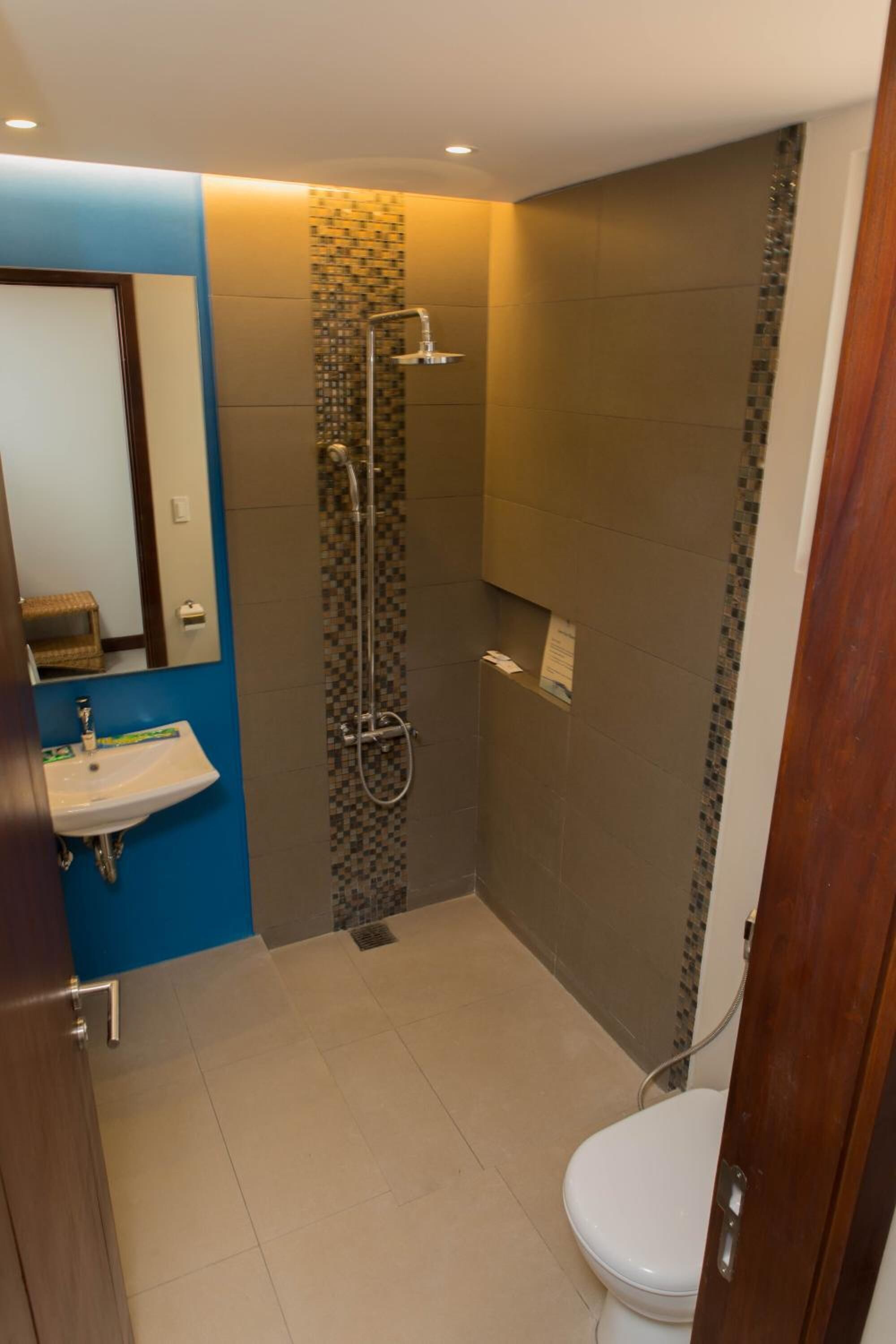 A bathroom with a shower, toilet, sink, and a mirror.