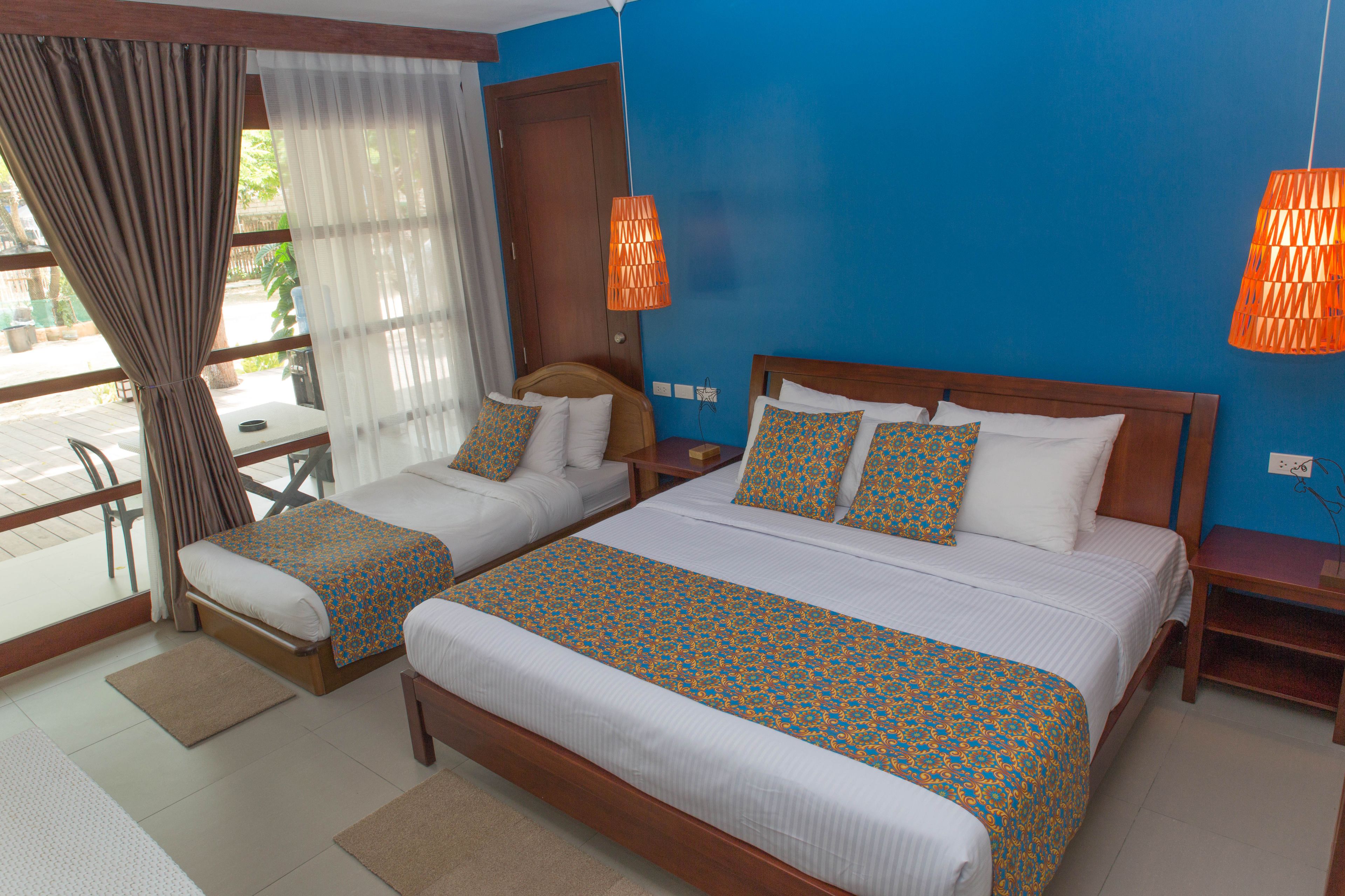 A hotel room with two beds, a wooden headboard, a small table, and a chair.