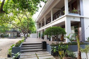 A modern building with a covered outdoor area, steps leading to a balcony, and various potted plants. - Karancho Beach House (Lapu-Lapu)