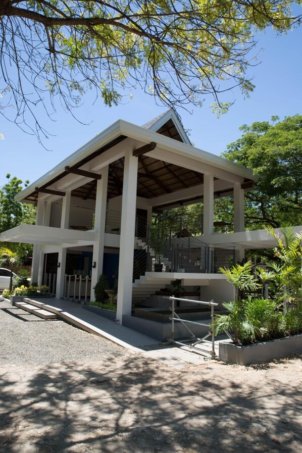 A modern building with a covered entrance, multiple floors, and a staircase leading to the upper levels. - Karancho Beach House (Lapu-Lapu)