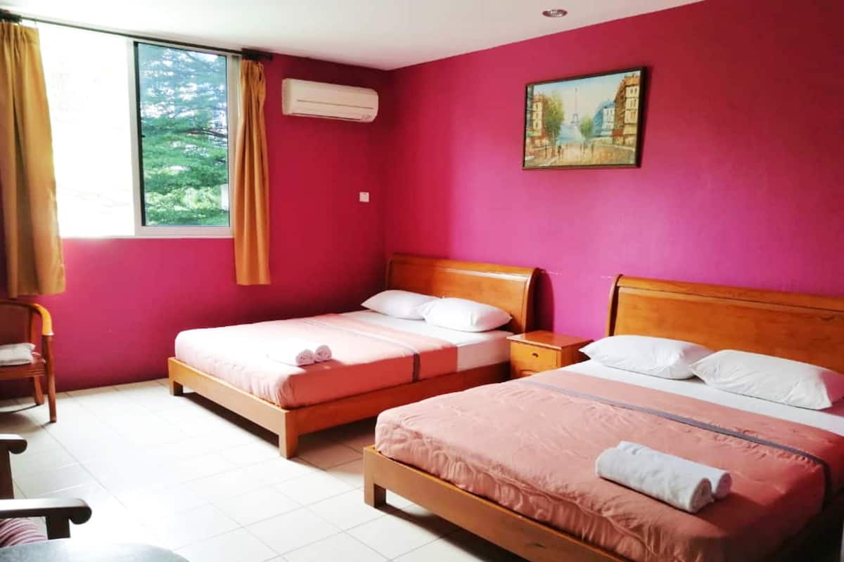 A room with two beds, a chair, and a window with curtains.