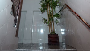 A staircase with a metal railing, a potted plant, and a wall with a decorative element. - John's Place (Kuching)