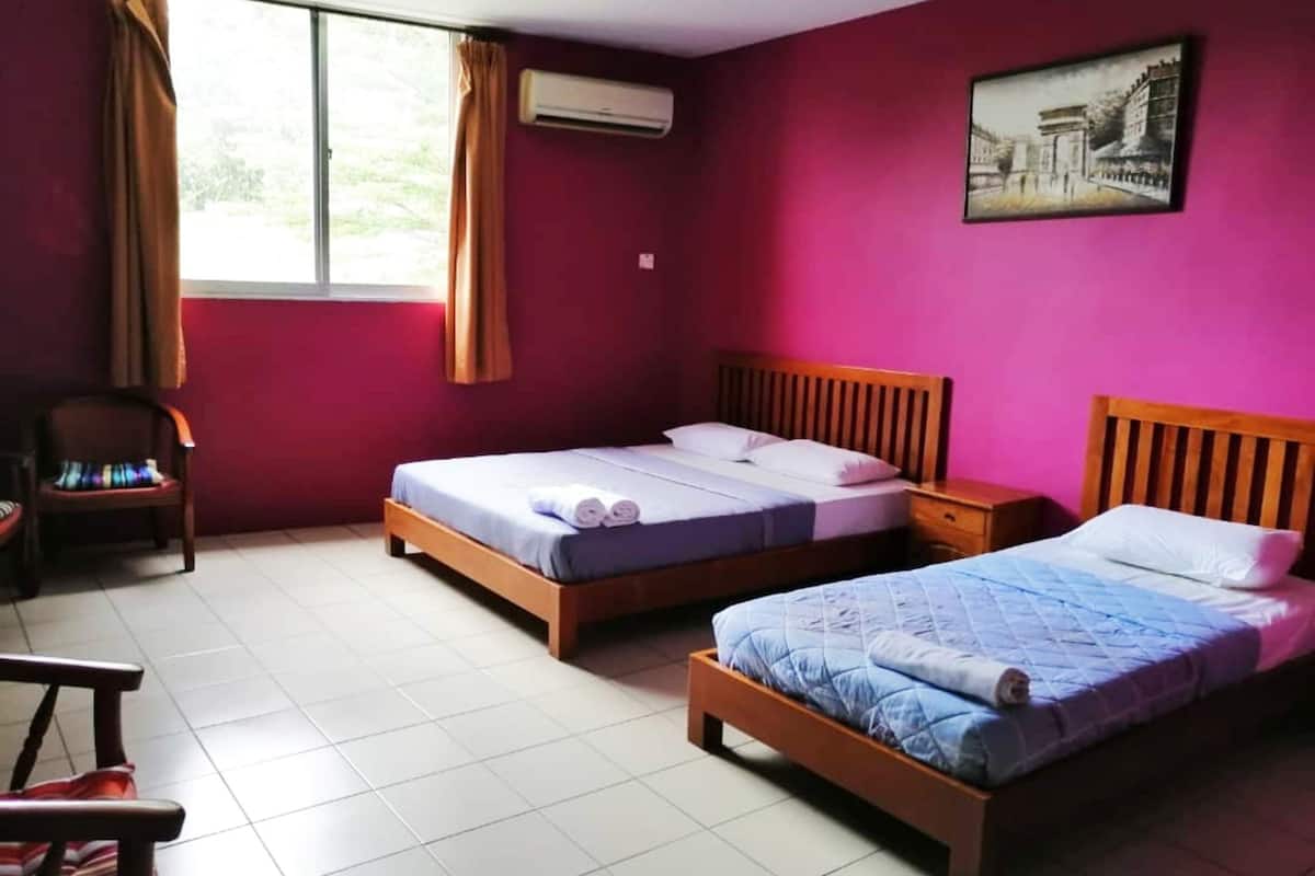 A room with two beds, a chair, and a window with curtains.